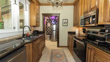 A kitchen with wooden cabinets, stainless steel appliances, a chandelier, and a patterned rug.