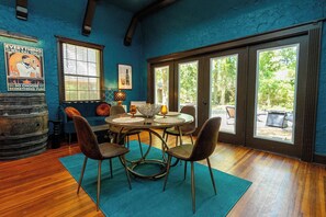 A dining area with a round table, four chairs, a blue rug, and a poster on the wall.