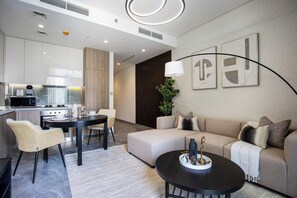 A modern living room with a sofa, a coffee table, and a dining area with chairs and a table. - New Waterfront 1B with Skyline & Canal View (Dubai)