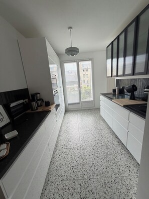 A modern kitchen with white cabinetry, a black countertop, and a speckled tile floor. - Tremendous 1-bedroom apartment in cool Le Havre near the beach (Le Havre)