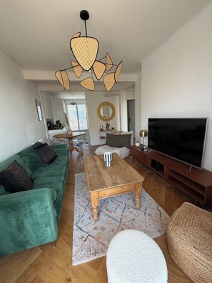 A modern living room with a green sofa, a wooden coffee table, a TV, and a unique ceiling light fixture. - Tremendous 1-bedroom apartment in cool Le Havre near the beach (Le Havre)