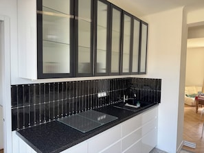 A modern kitchen with black countertops, white cabinetry, and a black backsplash. - Tremendous 1-bedroom apartment in cool Le Havre near the beach (Le Havre)