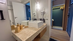 Casa de banho moderna com um espelho grande, duas pias, um secador de cabelo e um chuveiro amplo.