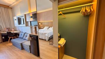 A hotel room with a bed, a desk, a TV, a mini-fridge, and a bathroom with a towel rack.