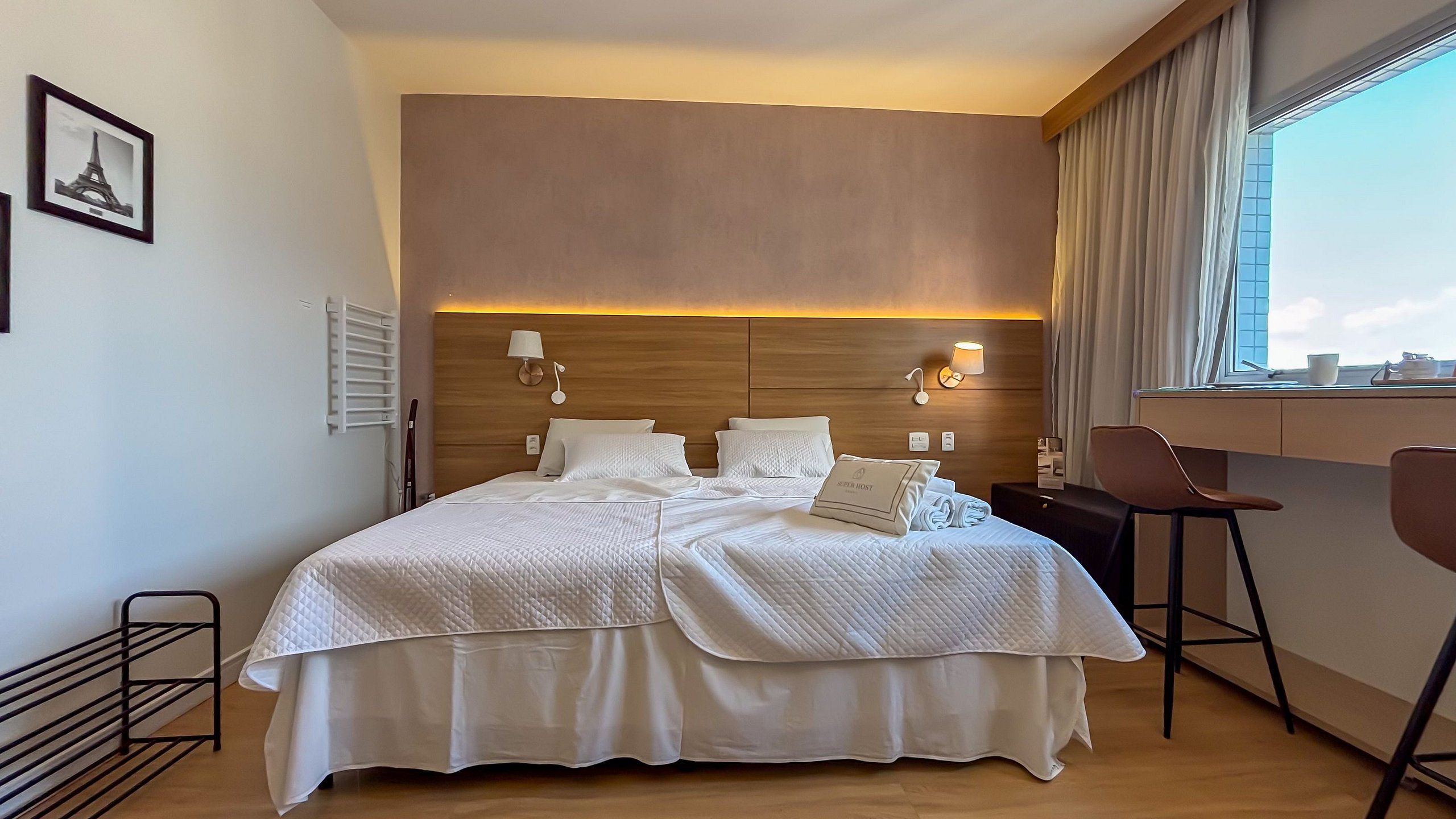 A hotel room with a large bed, bedside lamps, a desk, and a chair.