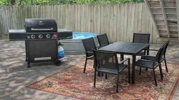 En uteplats med en grill, ett bord, stolar och en bubbelpool.