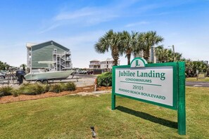 Schild für die Jubilee Landing Eigentumswohnungen mit Blick auf ein Gebäude und ein Boot im Hintergrund.