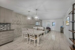 A modern kitchen with a dining area, wooden wall paneling, and pendant lighting. - Old River Landing /Jubilee Landing 306/Boaters Welcome/Outdoor Pool (Orange Beach)