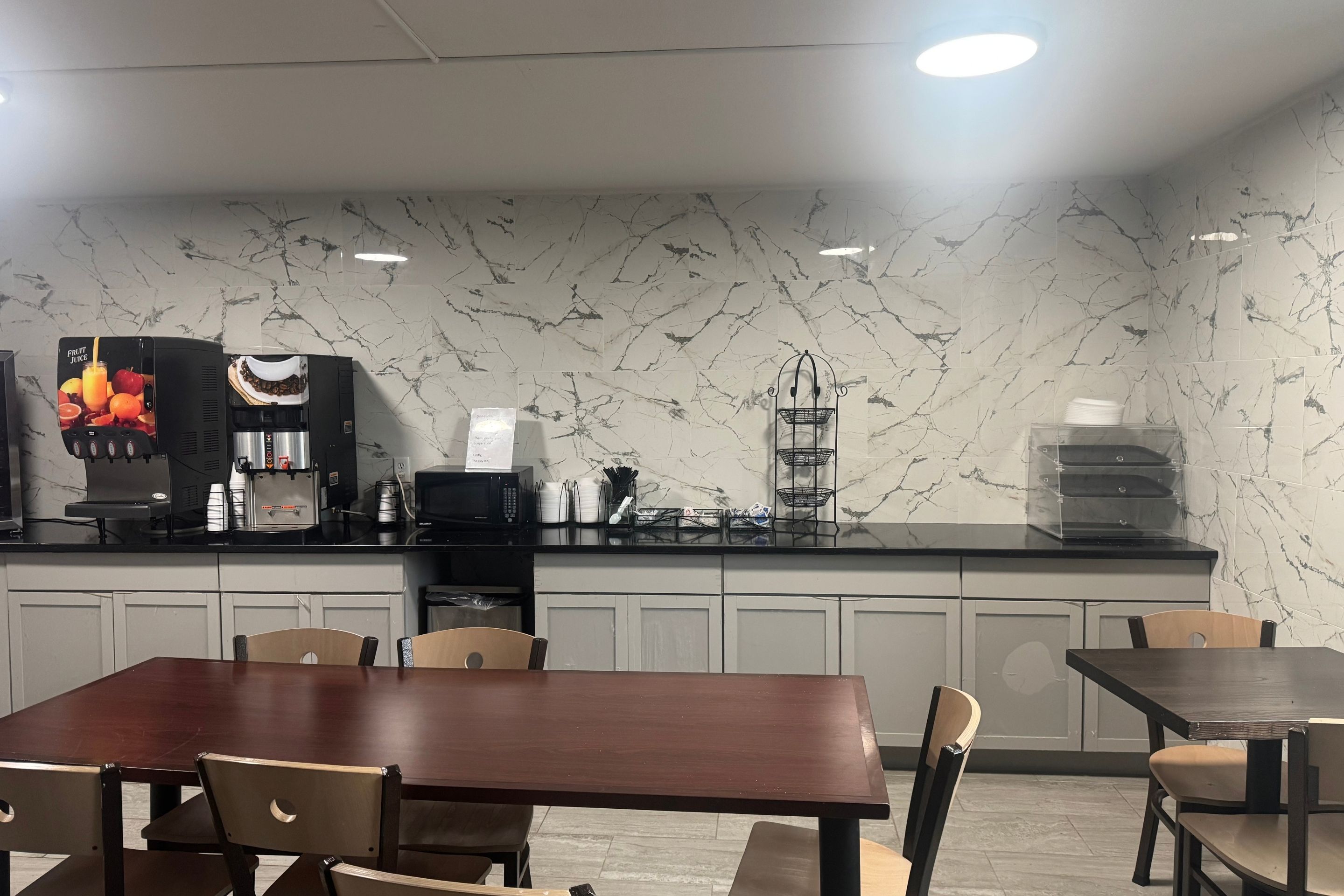A modern kitchen with a marble backsplash, a coffee machine, and a water dispenser.