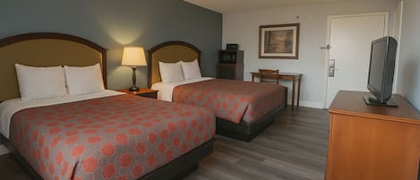 Habitación de hotel con dos camas, un televisor, una mesita y una puerta.