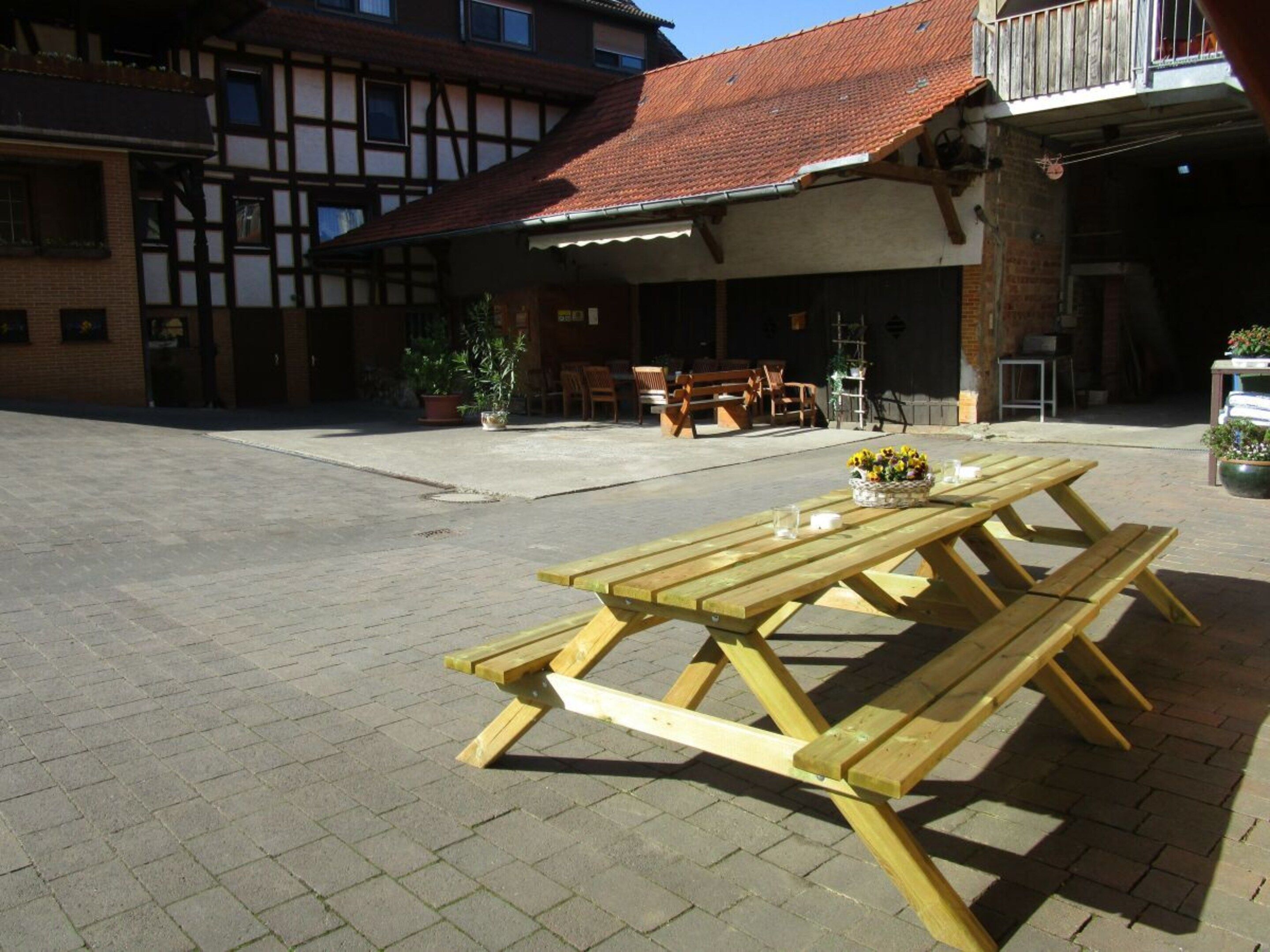Ein Sitzbereich im Freien mit Picknicktischen und Pflanzen in Töpfen.