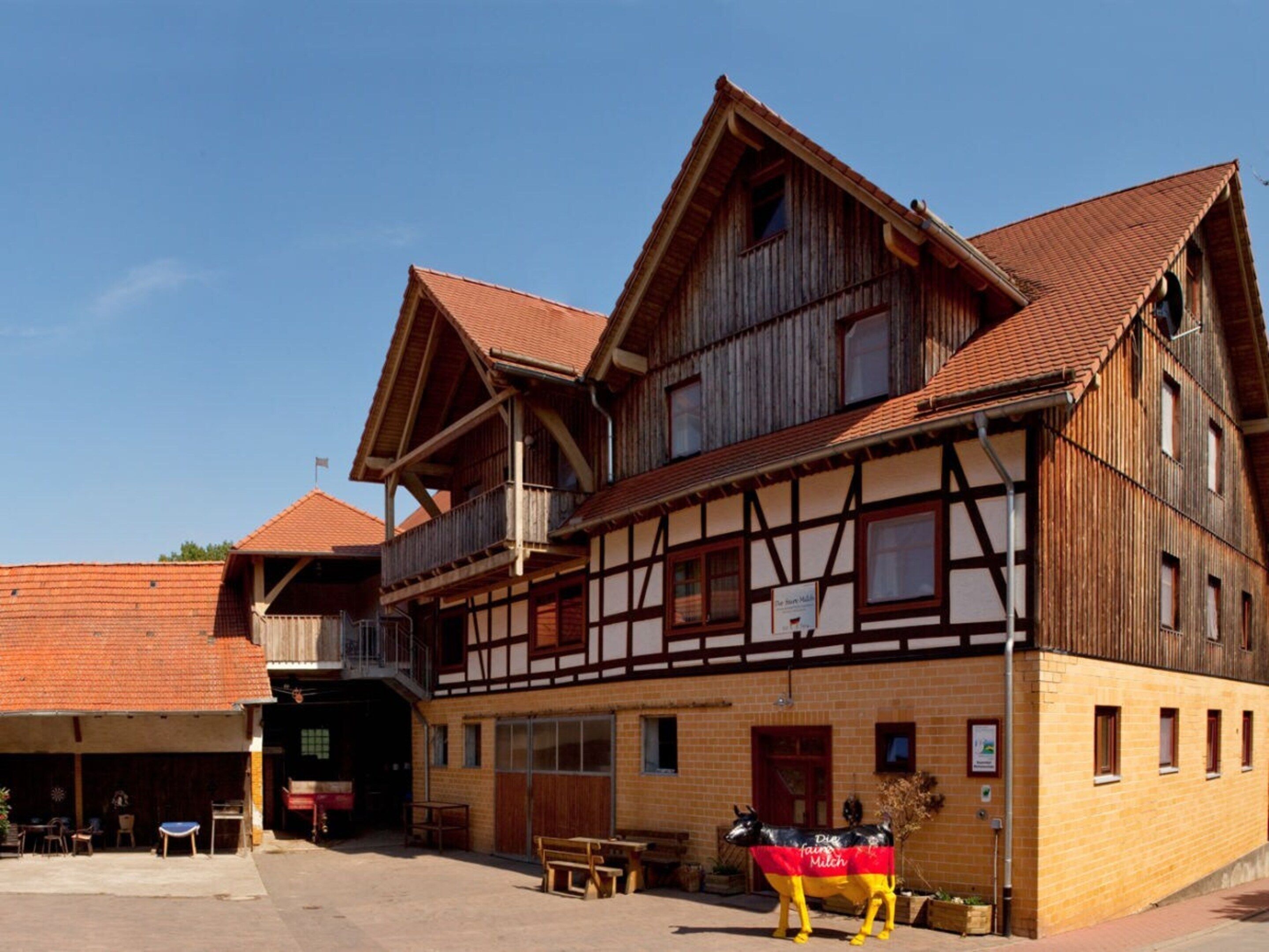 Ein traditionelles Fachwerkhäuschen mit Balkon und einer Pferdestatue davor.