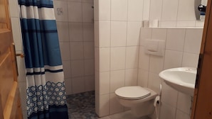 Un baño pequeño con inodoro, lavamanos y cortina de ducha.