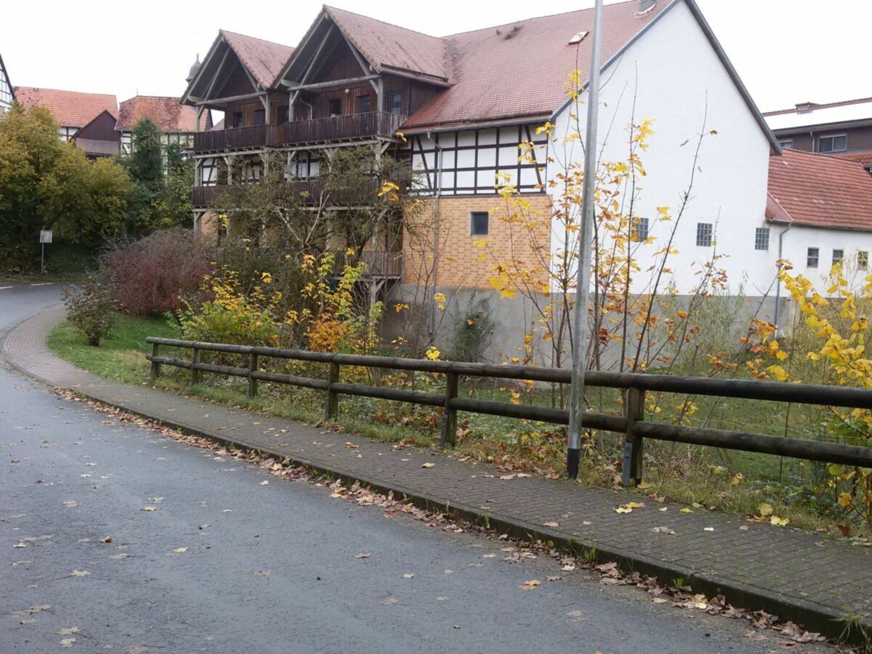 Een woonwijk met een verharde weg, houten hek en huizen met traditionele architectuur.