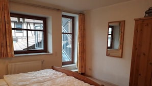 Un dormitorio con cama, ventana, puerta y armario.