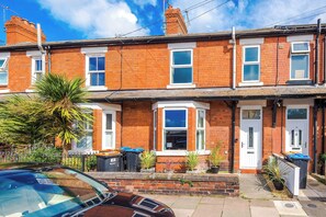 A row of terraced houses with brick facades, white window frames, and a car parked in the driveway. - Stunning New Home in Hoole, Chester! Sleeps 6 (Chester)