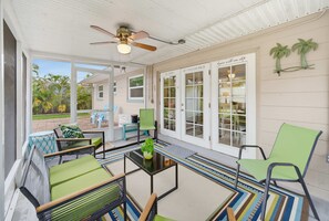 A covered outdoor seating area with chairs and a table, a ceiling fan, and a view of the garden. - St Pete Getaway Near Beaches Fenced Yard (St. Petersburg)