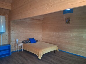 A wooden room with a bed, a small table, and a heater.