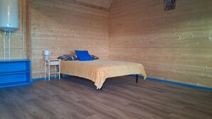Huone, jossa on sänky, yöpöytä, lamppu ja vedenkeitin.