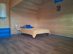 Een kamer met een bed, nachtkastje, lamp en een boiler.