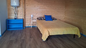 Makuuhuoneessa on sänky, yöpöytä, lamppu, lämmitin ja sininen hylly.
