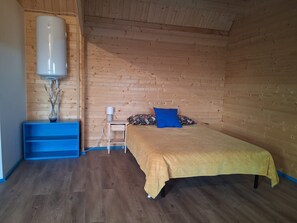 Een slaapkamer met een bed, nachtkastje, lamp, verwarming en een blauwe plank.