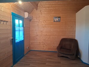 A room with wooden walls, a blue door, a brown chair, and a small picture on the wall.