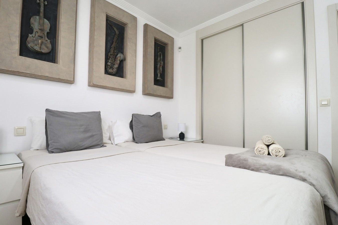 Una camera da letto con un letto, cuscini, un comodino e una cornice appesa al muro.