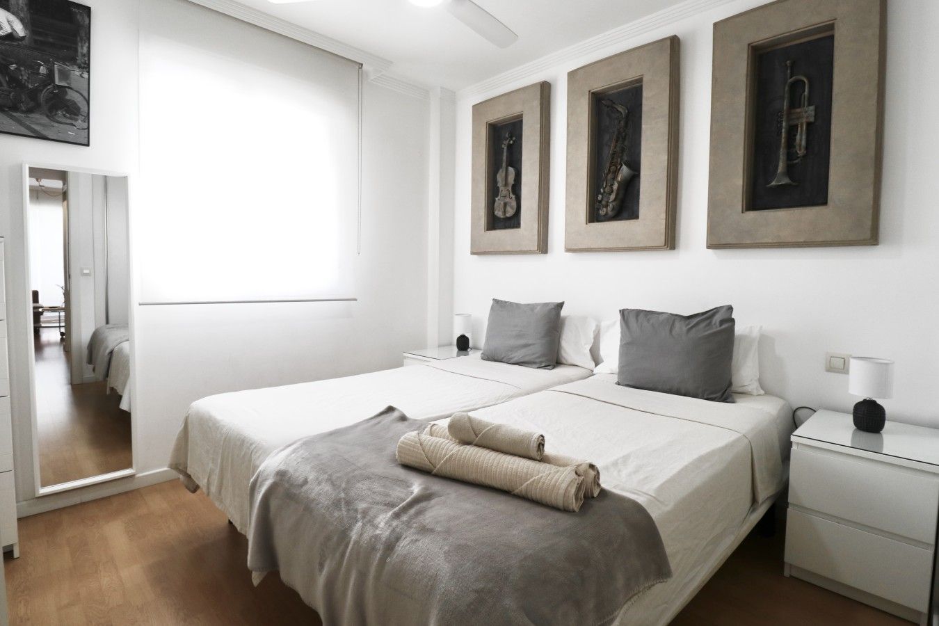 Ein Schlafzimmer mit einem großen Bett, zwei Nachttischen und einem Beistelltisch. An der Wand hängen drei gerahmte Bilder.