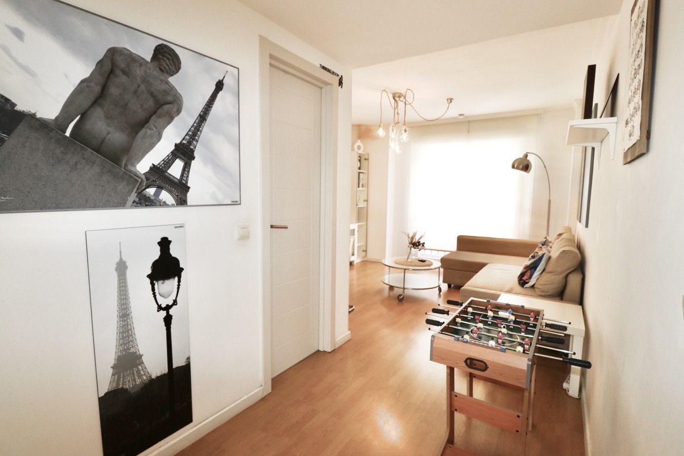 Een woonkamer met een bank, een tafelvoetbalspel en kunstwerken van de Eiffeltoren.