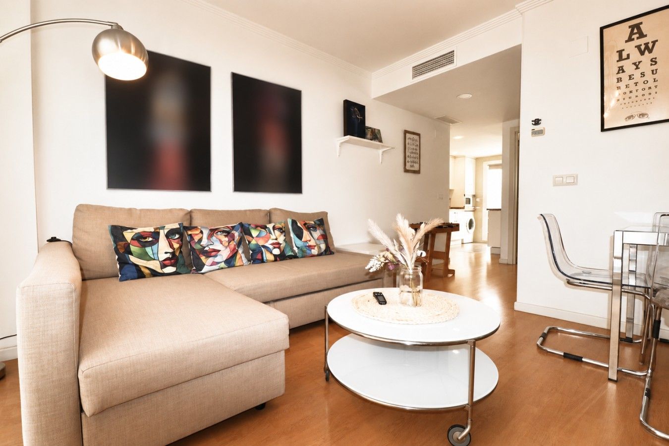 A living room with a beige sofa, a round coffee table, and a modern lamp.