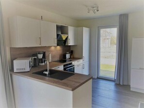 A modern kitchen with white cabinets, a wooden countertop, and a built-in oven. - House No. 37, Holiday Home Deichgraf (Wangerland)