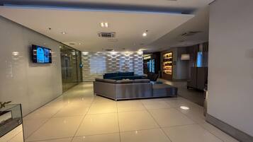 A modern lobby with a sofa, a TV, and a patterned wall.