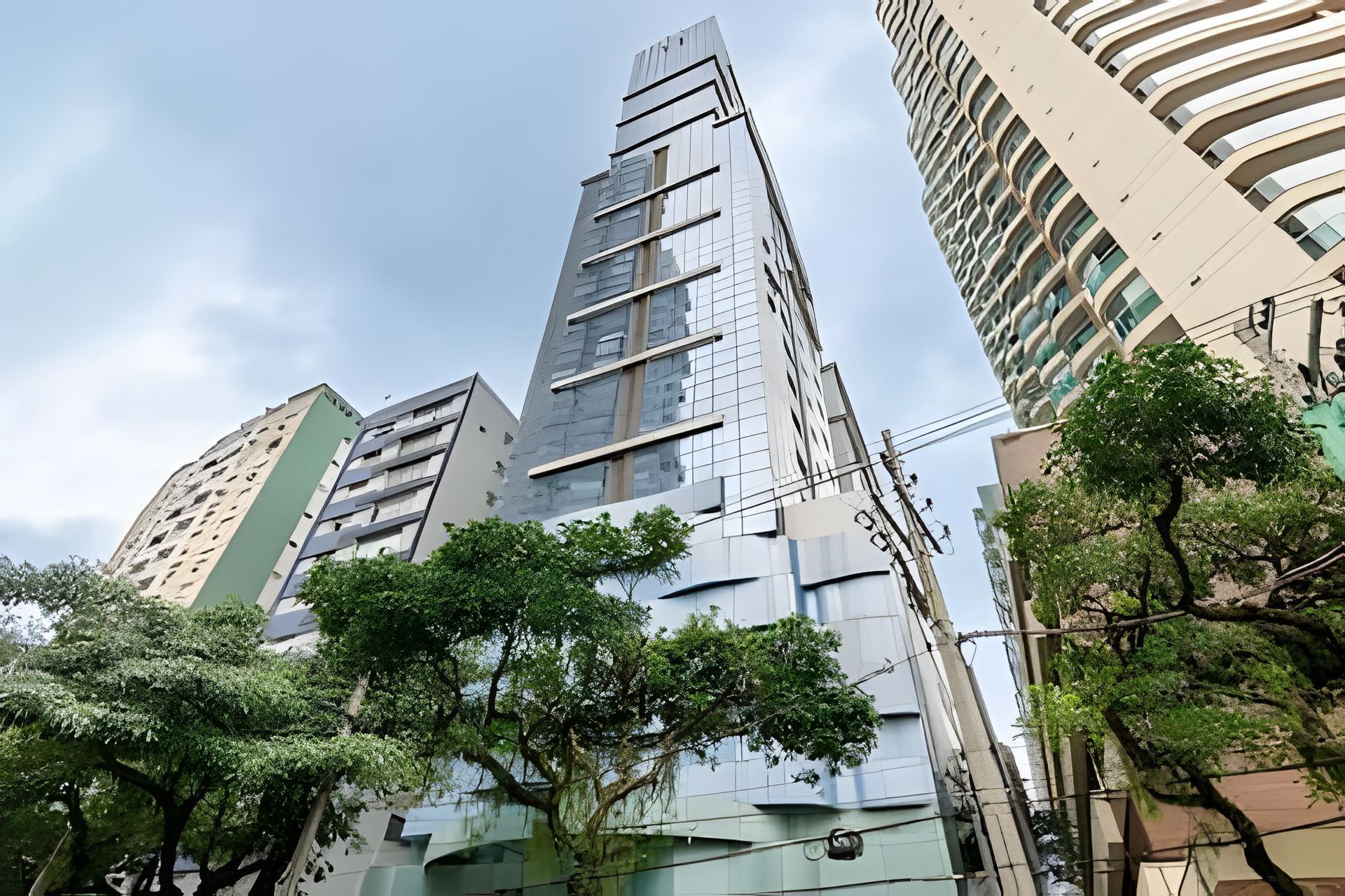 Un edificio moderno de gran altura con un diseño angular único, rodeado de otros edificios y árboles.