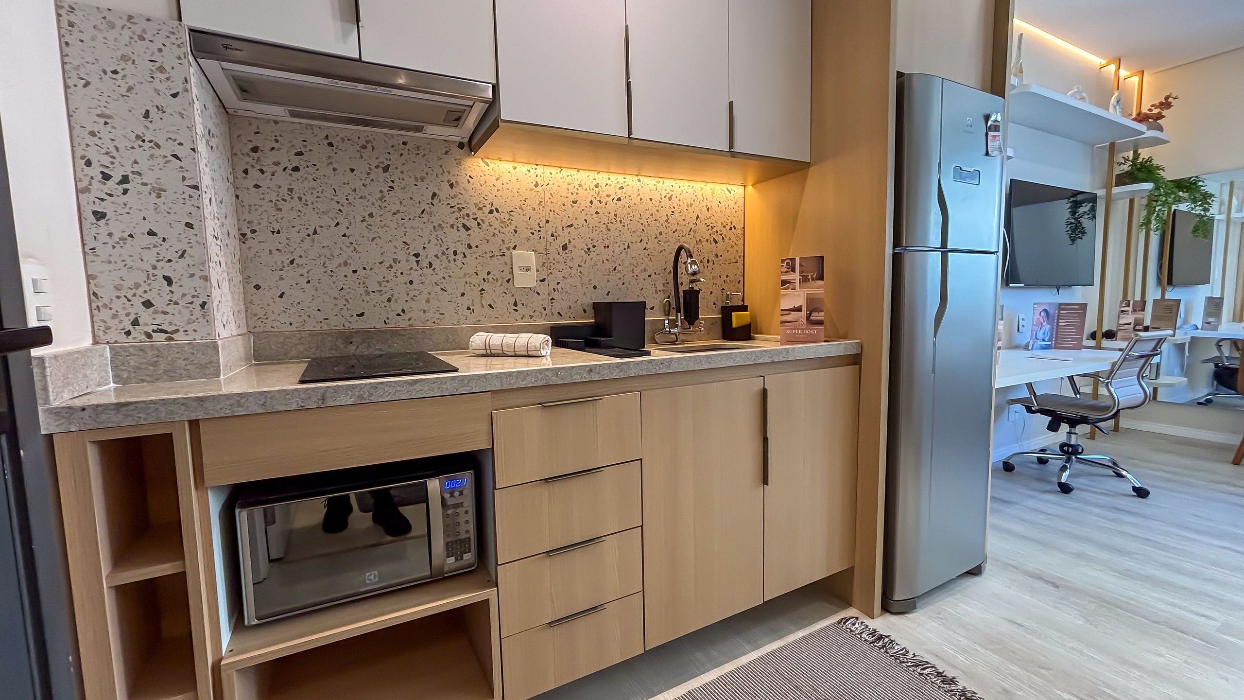 Una cocina moderna con horno integrado, refrigerador de acero inoxidable y una encimera con cafetera.