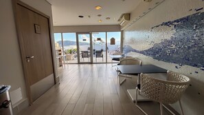 Quarto de hotel com varanda, parede revestida e vista para o mar.