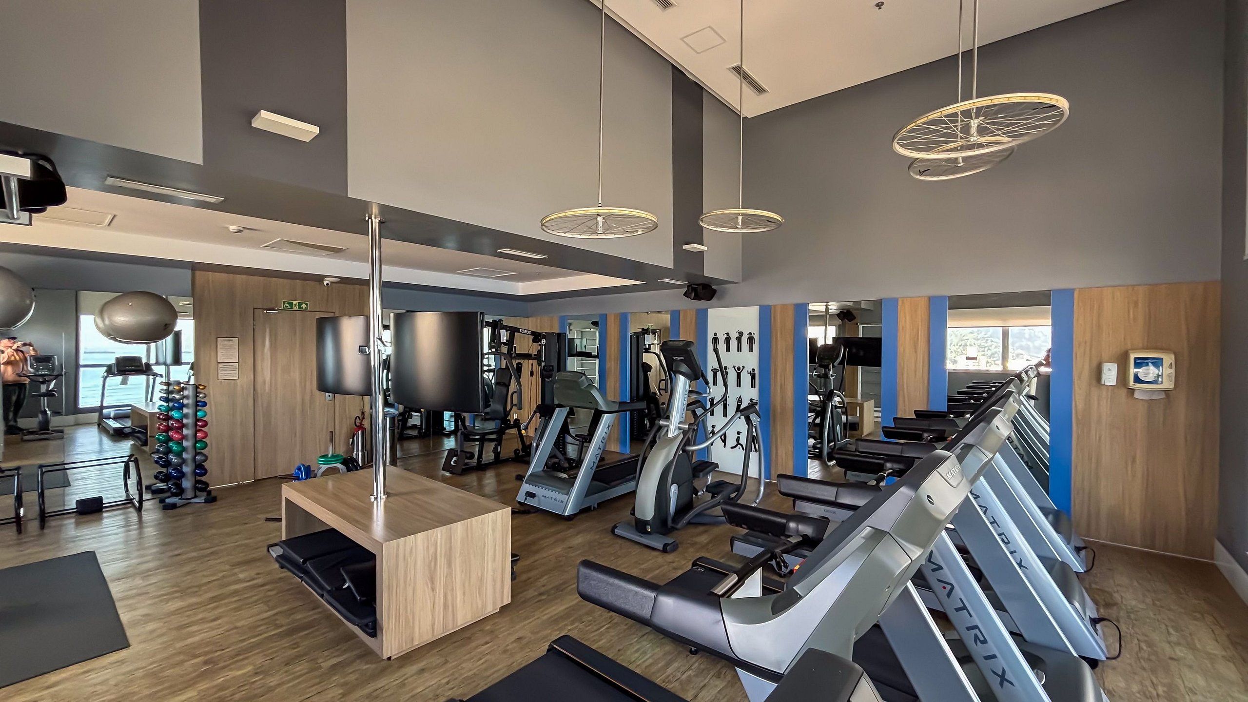 Un gimnasio con cintas de correr, máquinas de pesas y un muro de espejos.
