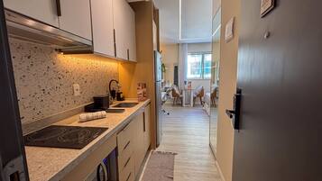 A modern kitchen with a granite countertop, a built-in oven, and a stainless steel refrigerator.