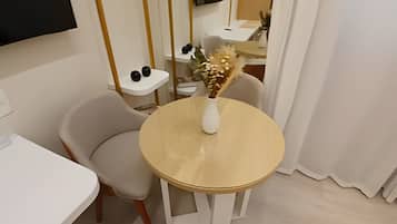 Un comedor moderno con una mesa redonda, una silla blanca y un jarrón con flores secas.
