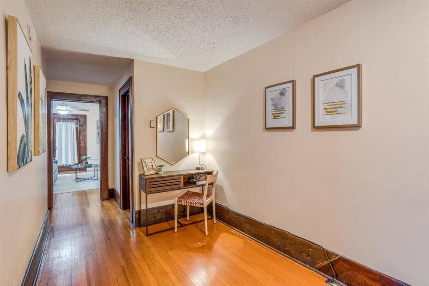 Warm hallway with hardwood floors, art, and a charming desk nook