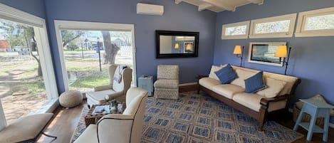 Una sala de estar con ventilador de techo, un sofá, un tapete estampado y un televisor.