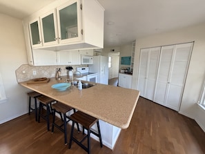 A kitchen with a central island, white cabinets, and a wooden countertop. - Journey by the Sea ~ Rockport, Texas (Rockport)