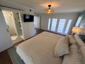Ein Schlafzimmer mit einem großen Bett, einem Fernseher und einem Deckenventilator.