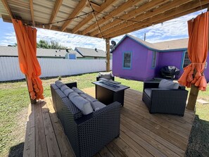 Eine Terrass mit Korbmöbeln und einem überdachten Bereich.