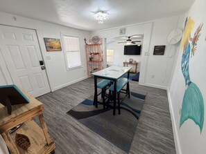 A dining area with a table and benches, a ceiling fan, and a wall-mounted TV. - Mermaid on Murray - Rockport (Rockport)