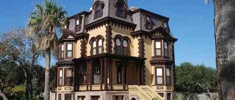 A large, historic building with multiple stories, a prominent central tower, and a grand entrance with a staircase.