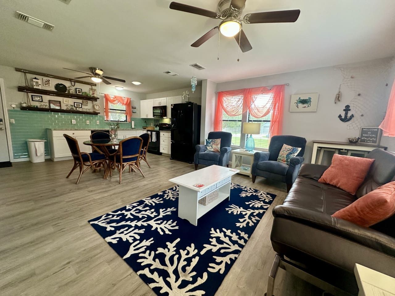 A living room with a sofa, armchairs, a coffee table, and a dining area with chairs and a table.