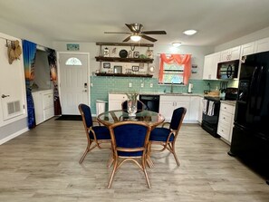 A kitchen with a dining table, chairs, a ceiling fan, and a refrigerator. - Rockport Runaway Retreat (Rockport)