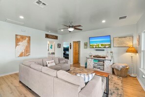 A modern living room with a sectional sofa, a flat-screen TV, and a ceiling fan. - Salty Vibes ~ Canal Front (Rockport)