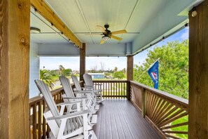 A covered porch with wooden railings, ceiling fan, and Adirondack chairs. - Salty Vibes ~ Canal Front (Rockport)